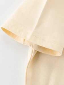 Close-up of a light yellow cotton short-sleeve T-shirt showing detailed double-needle stitching