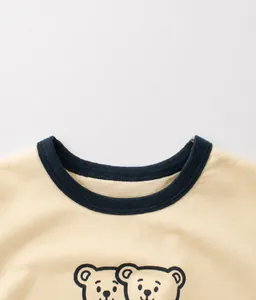 Detail of baby cotton t-shirt with beige fabric, blue ribbed collar and bear cartoon