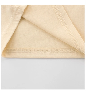 Detailed macro view of cream-colored knit shirt showing high-quality double-needle hem stitching
