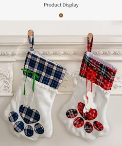 Detail of buffalo plaid paw-shaped Christmas stockings with bone and fish charms by fireplace