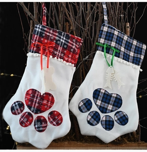 Close-up of paw-shaped Christmas stockings in red and blue plaid with festive bone charms
