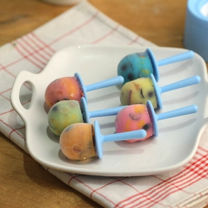 Molde para mini polos de 6 cavidades con helados coloridos caseros en un plato de cerámica
