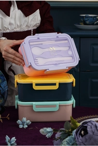 Detalle de fiambrera de tres compartimentos con cubiertos y diseño artístico dorado