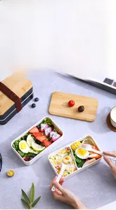 Macro detail of a double-layer black bento box with a bamboo lid and utensils