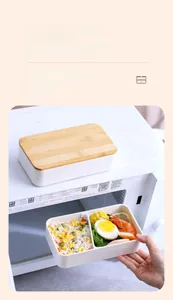 Dual-layer lunch box with bamboo lid showing bento compartments and food styling