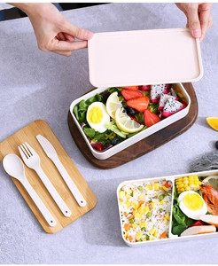 Detail of double-layer bento box with bamboo lid, utensils, and partitioned food storage