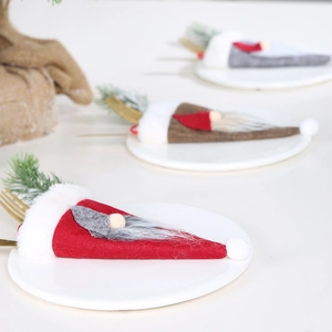 Primer plano de porta cubiertos de gnomos navideños en platos blancos decorativos