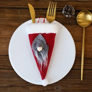 Detalle de una funda de cubiertos navideña con gnomo y cubiertos dorados en plato