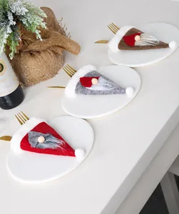 Detalle de cubierteros navideños de gnomo en rojo, gris y café en un plato blanco