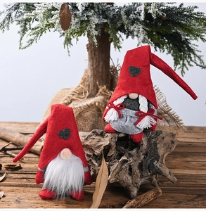 Close-up of plush Christmas gnomes with red heart hats and white braids on wood