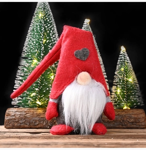 Close-up of Christmas gnome plush with red heart hat and long white beard on wooden base