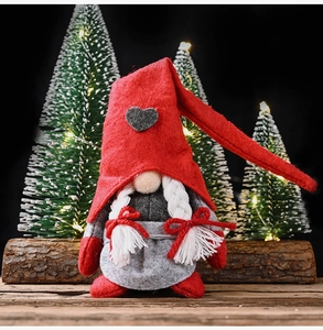 Detail of Christmas gnome plush with red heart hat, white braids and festive accessories