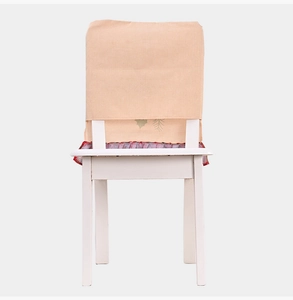 Detail of Christmas burlap chair cover featuring green leaf patterns and red ruffled edges