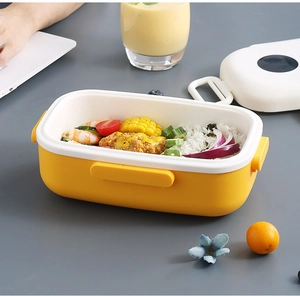 Fiambrera rectangular amarilla y blanca con asa mostrando capas de arroz y verduras