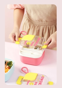 Close-up of a pink stainless steel bento box for kids with a white spoon and food