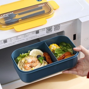Blue 1100ml bento box with utensils being placed into a microwave for heating