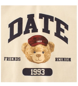 Detail of vintage teddy bear print with Luck and Date text on a cream cotton kids t-shirt