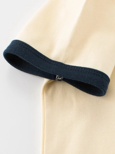 Close-up of beige cotton kids T-shirt featuring navy blue ribbed ringer sleeve cuffs