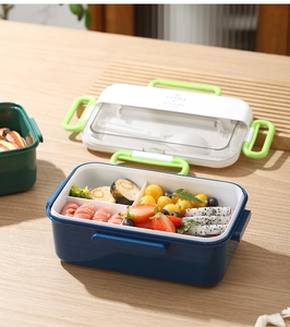 Close-up of compartmentalized bento box with leak-proof lid and portable green handle