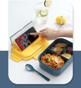 Detail of the multi-compartment lunch box lid featuring a built-in mobile phone holder