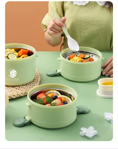 Detail of mint green tiered lunch box with spaceman logo and portable cutlery set