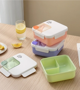 Fiambrera cuadrada con tres compartimentos y espacio para cubiertos en mesa madera