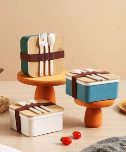 Trois boîtes à bento japonaises avec couvercles en bambou et couverts sur un socle en bois