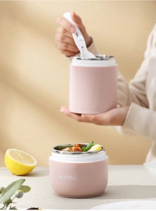 Gros plan des boîtes à lunch isothermes en acier rose avec cuillères pour le petit-déjeuner