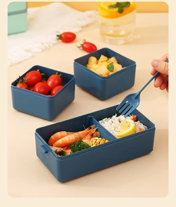 Close-up of deep blue double-layer bento box with divided sections and utensils