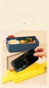 Detail of blue double-layer lunch box lid used as a phone holder with interior compartments