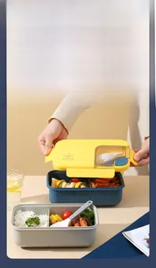 Detail of partitioned lunch box with yellow lid, snap locks, and utensil storage