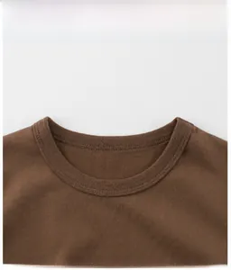 Macro detail of the ribbed crew neck and fine double-stitched seams on the brown cotton T-shirt