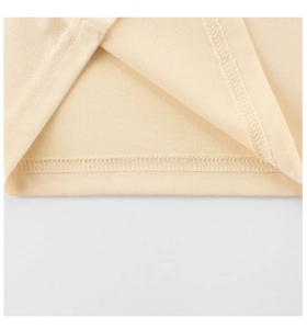 Close-up of double-stitched hem on beige cotton knit t-shirt showing fine craftsmanship