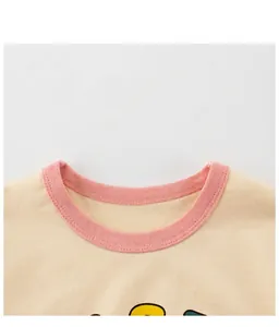 Détail du col rond rose contrasté et double surpiqûre sur t-shirt jaune pour bébé