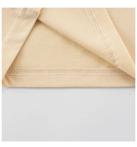 Gros plan de l'ourlet à double couture et surjet sur un t-shirt beige pour enfant