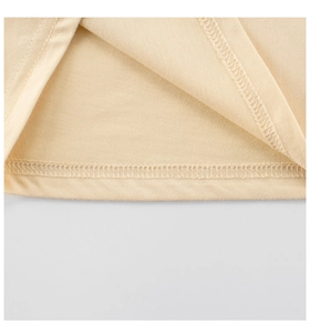 Macro-opname van de dubbele naaldsteek op de zoom van een crème katoenen kinder t-shirt