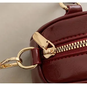 Detailed close-up of premium gold zipper and hardware on deep red leather handbag