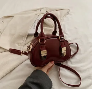 Close-up of wine red leather mini Boston bag with gold hardware and shoulder strap