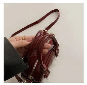 Close-up of wine red patent leather bowling bag showing round handles and gold zippers