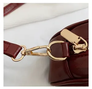 Macro shot of gold-tone hardware hooks and zipper on premium wine red leather handbag