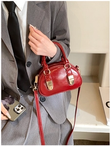 Detail of burgundy glossy leather mini bowling bag with gold metal hardware and slim strap