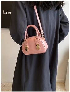 Close-up of pink mini bowling bag with gold buckles and adjustable strap on a model