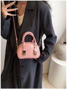 Detail shot of a small pink bowling bag featuring glossy leather and golden metal buckles