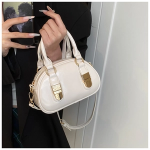 Close-up of cream white glossy leather bowling bag with gold hardware and hand strap