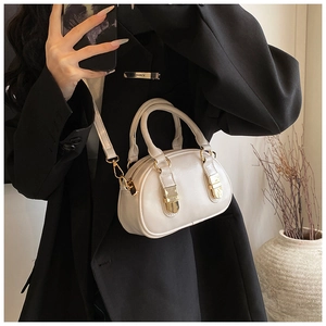Detail of cream white shell-shaped bowling bag with golden buckles and leather texture