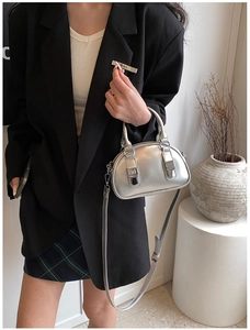 Model showcasing a silver mini Boston bag with metallic texture and sleek double handles