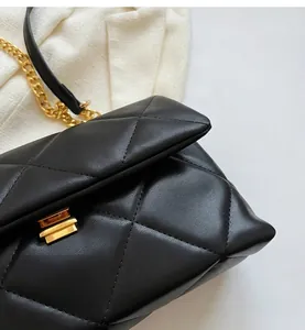 Detail of black quilted leather handbag featuring gold metal chain and square turn-lock