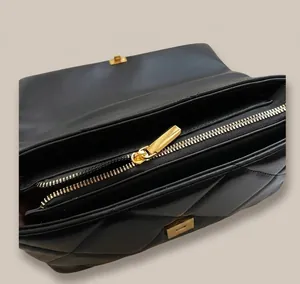 Detailed view of internal compartments and smooth gold metal zipper on black quilted bag