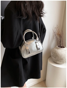 Detail of silver metallic mirror bowling bag with dual handles and sleek crossbody strap