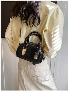 Black bowling bag held by a model with natural blinds shadow lighting for a retro feel